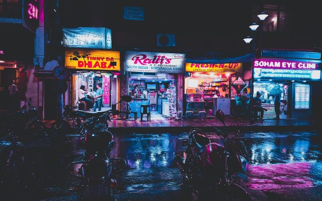 城市夜景中的霓虹街道，一部都市题材日剧的剧照氛围，湿漉漉的路面映着暖橙色灯光